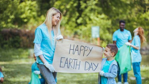 Adult and youth holding a sign saying happy earth day 
