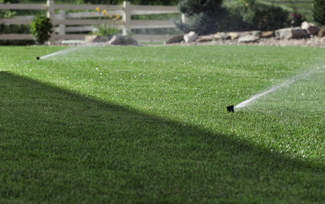 Lawn sprinkler heads spraying water on green grass