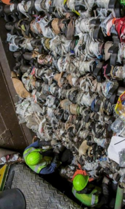 Roller bars fill with tangled plastic bags and two workers at the bottom cutting them off. 