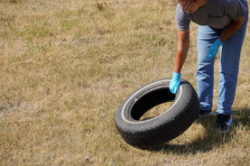 Man holding a tire with grass in the background