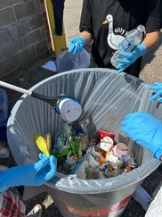 Trash bin with trash grabbers pulling recycling items out