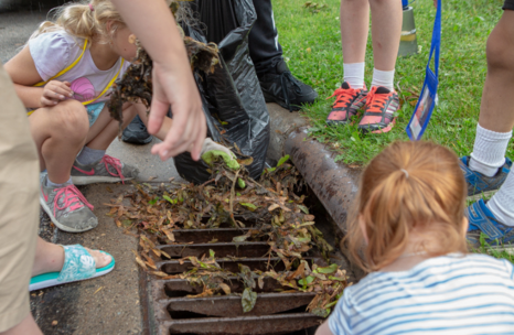 Students help clean debris from a storm drain as part of the Adopt a Drain program