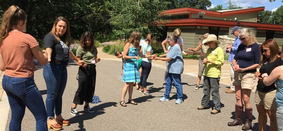 Educators standing in a semi-circle passing beads during a Project WET activity demonstration