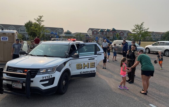 Families interacting with police officers and looking at police SUV at night to unite