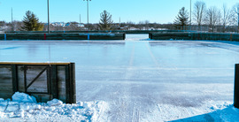 Image of two ice rink freshly iced one in front of the other with wood edging enclosing it.