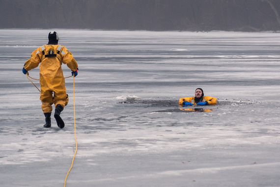 Firefighters practicing ice rescue on frozen lake in bright yellow rescue suits