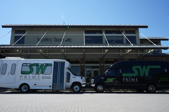 Two SouthWest Prime Buses nose to nose in front of a SouthWest Transit building