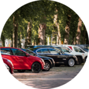 Cars are parked along a tree-lined street in a shaded downtown area.