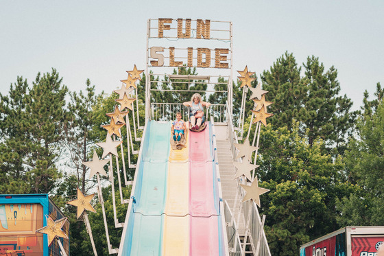A child and an adult ride side by side down a colorful Fun Slide at Chanhassen’s Fourth of July Celebration.