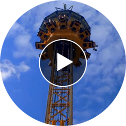 Video thumbnail of riders high atop a yellow drop tower carnival ride against a blue sky.