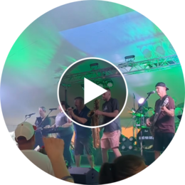 Video preview of a live band performing under a tent with green stage lighting.