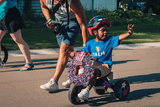 A child rides a decorated tricycle in the 4th of July Kiddie Parade.