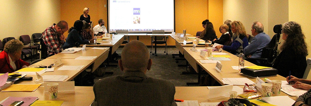 Council members sitting at a table and a screen is showing in the background