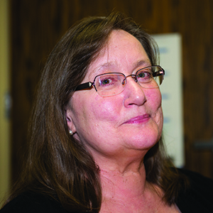 Margot Imdieke Cross has brown hair and glasses and is smiling. 