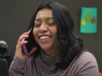 A Latina woman talks on the phone and smiles