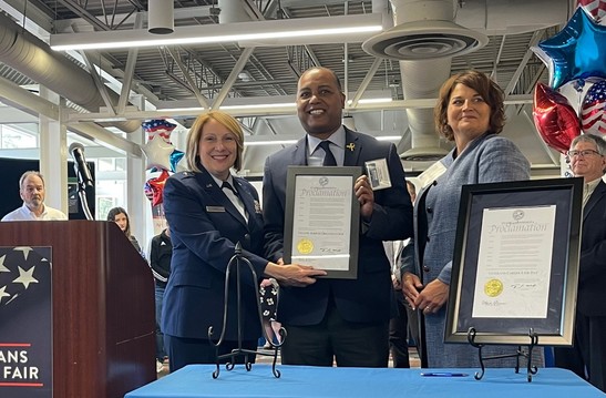 Deputy Commissioner Marc Majors standing with proclamation making DEED a yellow ribbon employer