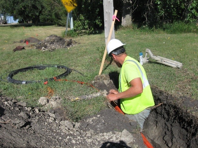 Construction worker burying cable.