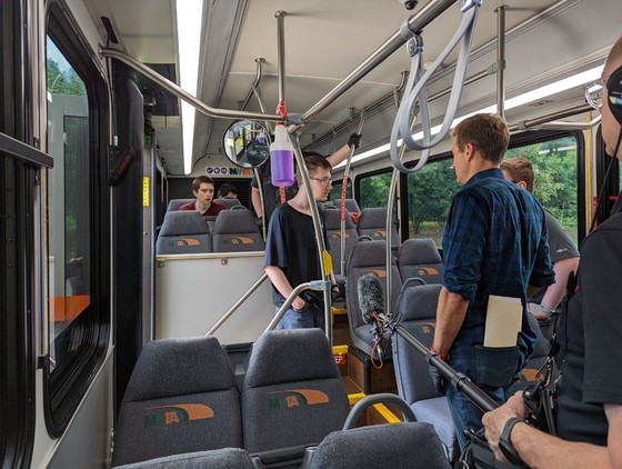 Commissioner talks with student workers on the inside of a bus