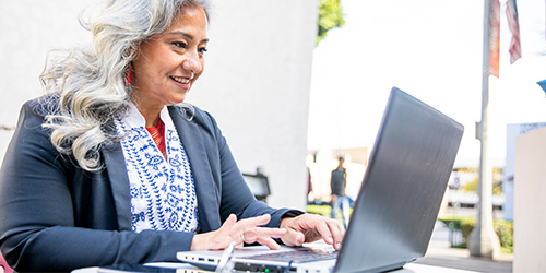 Woman sitting at a table working on her laptop.