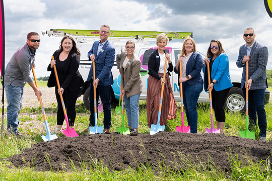 Attendees of event hold shovels over newly dug ground