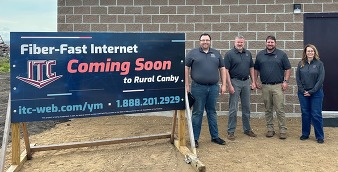 Group of 4 poses outside at event in front of organization's sign.