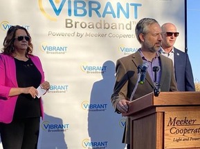 Three people around an outdoor podium at awards announcement
