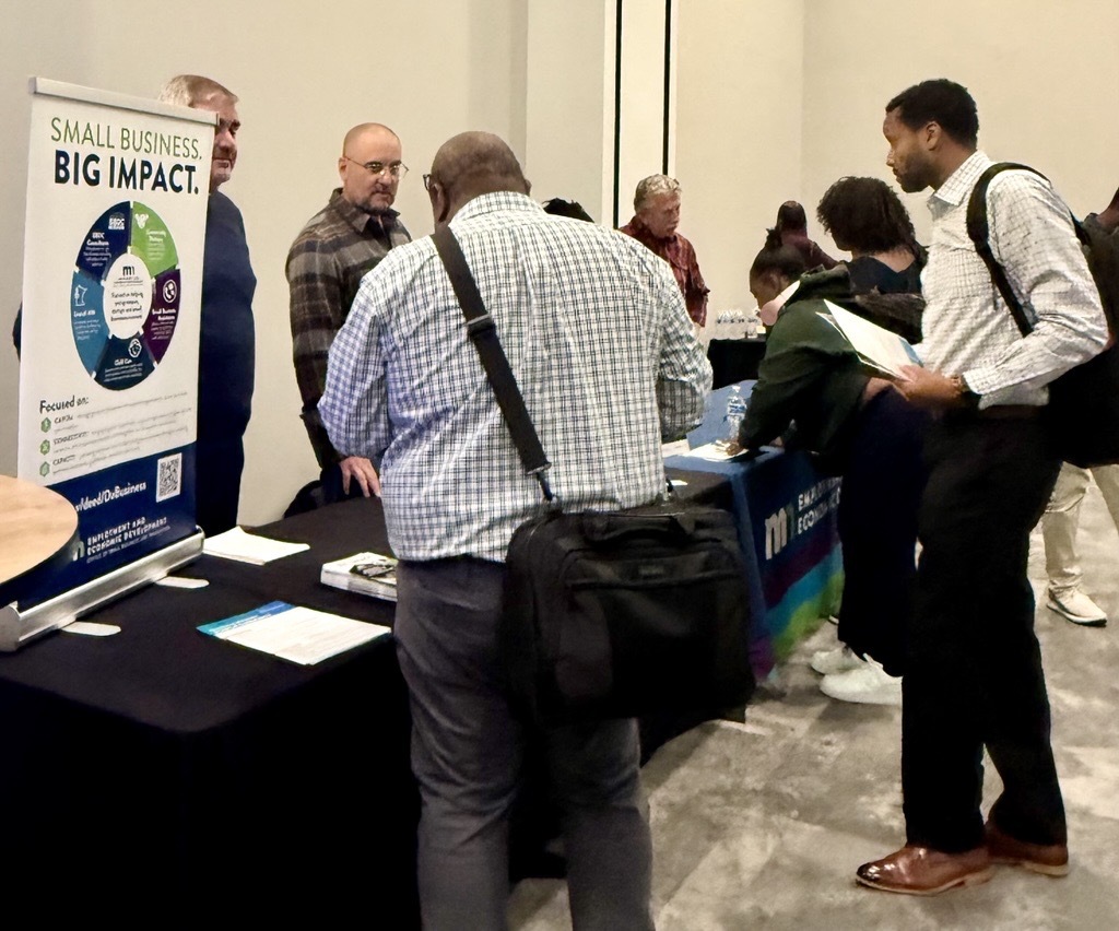 People gather around a table to receive input on their small business during TCSW.