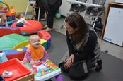 Commissioner Emily Piper plays with an infant at the Cougar Cub Child Care Center