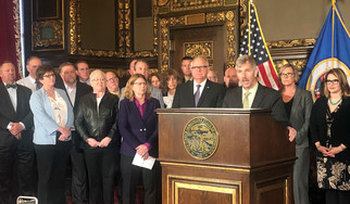Governor Walz and Commissioner Lourey at a podium surrounded by business executives