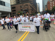 Staff walking in parade holding banner that says "Department of Human Services LGBTQ Employee Resource Group"