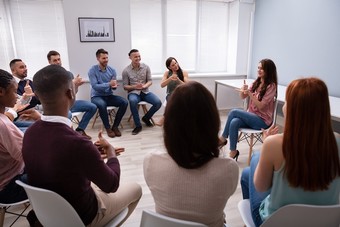 group of people seated in circle learning sign language
