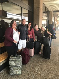 Four women and a man with suitcases