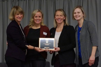 Commissioner Harpstead with three women from Sourcewell, posing with award plaque