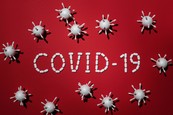 words "COVID-19" on red table with white models of the virus next to words