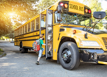 elementary school age boy getting on a school bus