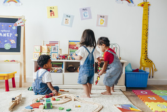 three young children playing in a playroom
