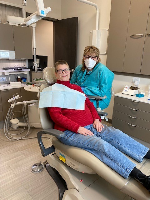 Dental assistant with adult female dental patient in dental chair