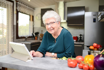Older woman in kitchen with tablet