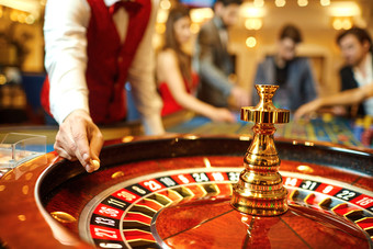 casino worker dropping ball on roulette wheel