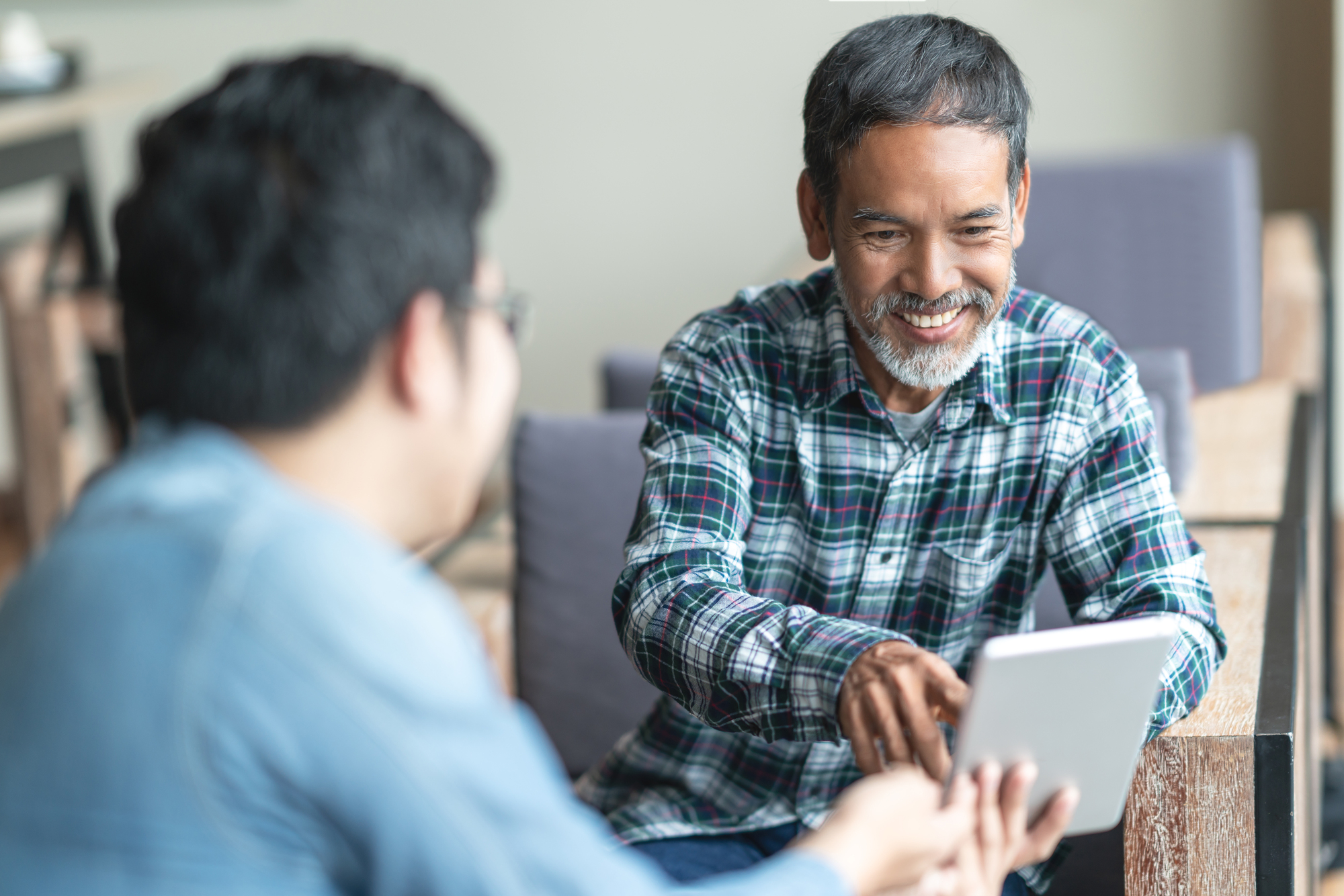 Two men using a tablet device to communicate.
