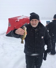 A man ice fishing and holding a fish