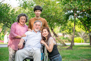 Elderly man in a wheelchair with his family in the park