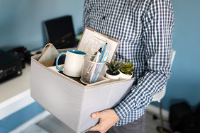 A person in a workplace setting carrying a box