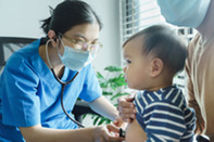 Doctor holding stethoscope to baby