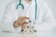 Doctor hand arranging wood block with healthcare medical icons. Health care and medical insurance concept.