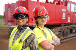 Two female construction apprentices smiling back to back