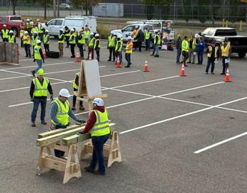 People in construction gear standing and working in parking lot