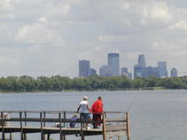 Several anglers on fishing dock on Lake Calhoun with Minnepolis skyline in background