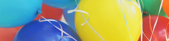 Photo of a person holding a number of brightly colored balloons