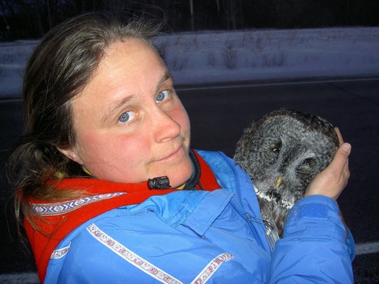 Woman in winter jacket cradling an owl